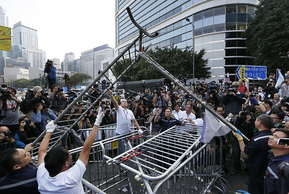 Workers start clearing away barricades at an occupied area outside government headquarters in Hong Kong Tuesday, Nov. 18, 2014. The removal comes after a Hong Kong court granted a restraining order against the protesters last week requiring them to clear the area in front of a tower in the central part of Hong Kong as well a separate order against a second protest site Mong Kok brought by taxi and minibus operators. (AP Photo/Kin Cheung)