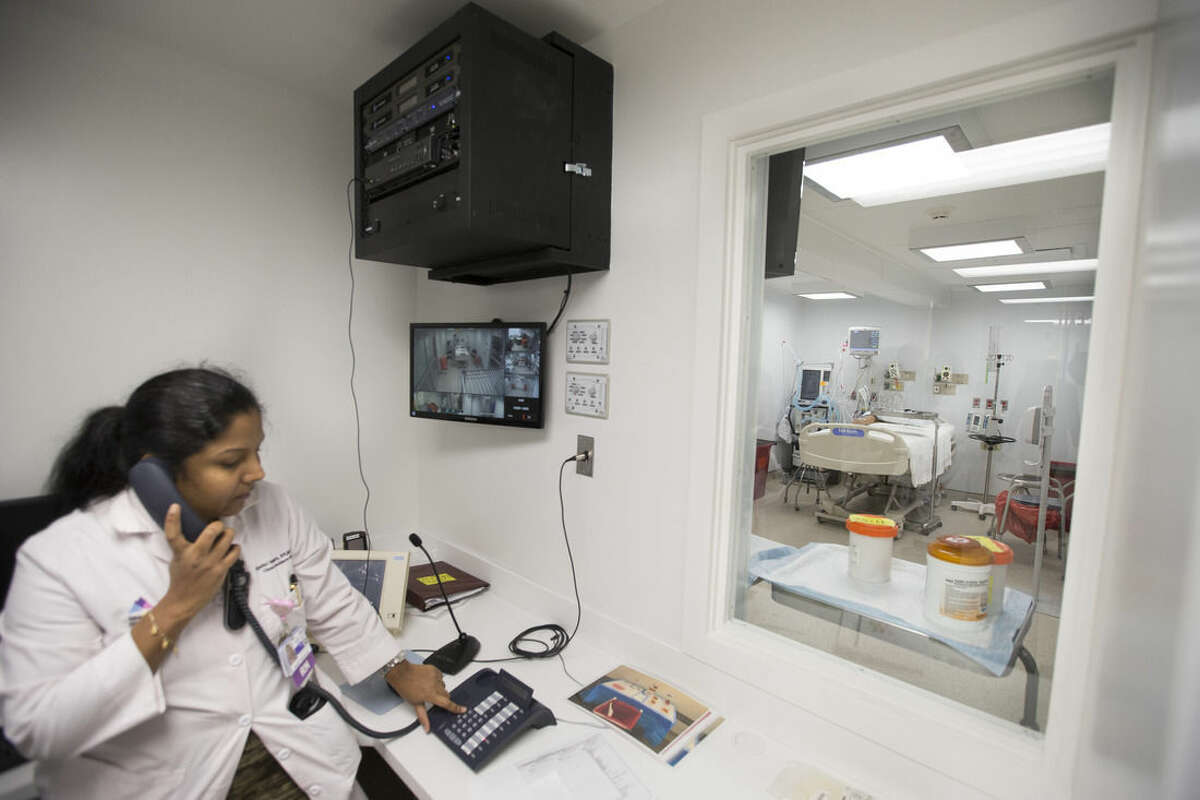 In this Friday, Nov. 14, 2014 photo, a nurse sits beside a closed-circuit monitoring system outside a patient care room in a new custom-built bio-containment unit for potential Ebola cases at Mount Sinai Hospital, in New York. The unit, built over two weeks, is completely separate from the main medical buildings and can house three patients simultaneously. (AP Photo/John Minchillo)