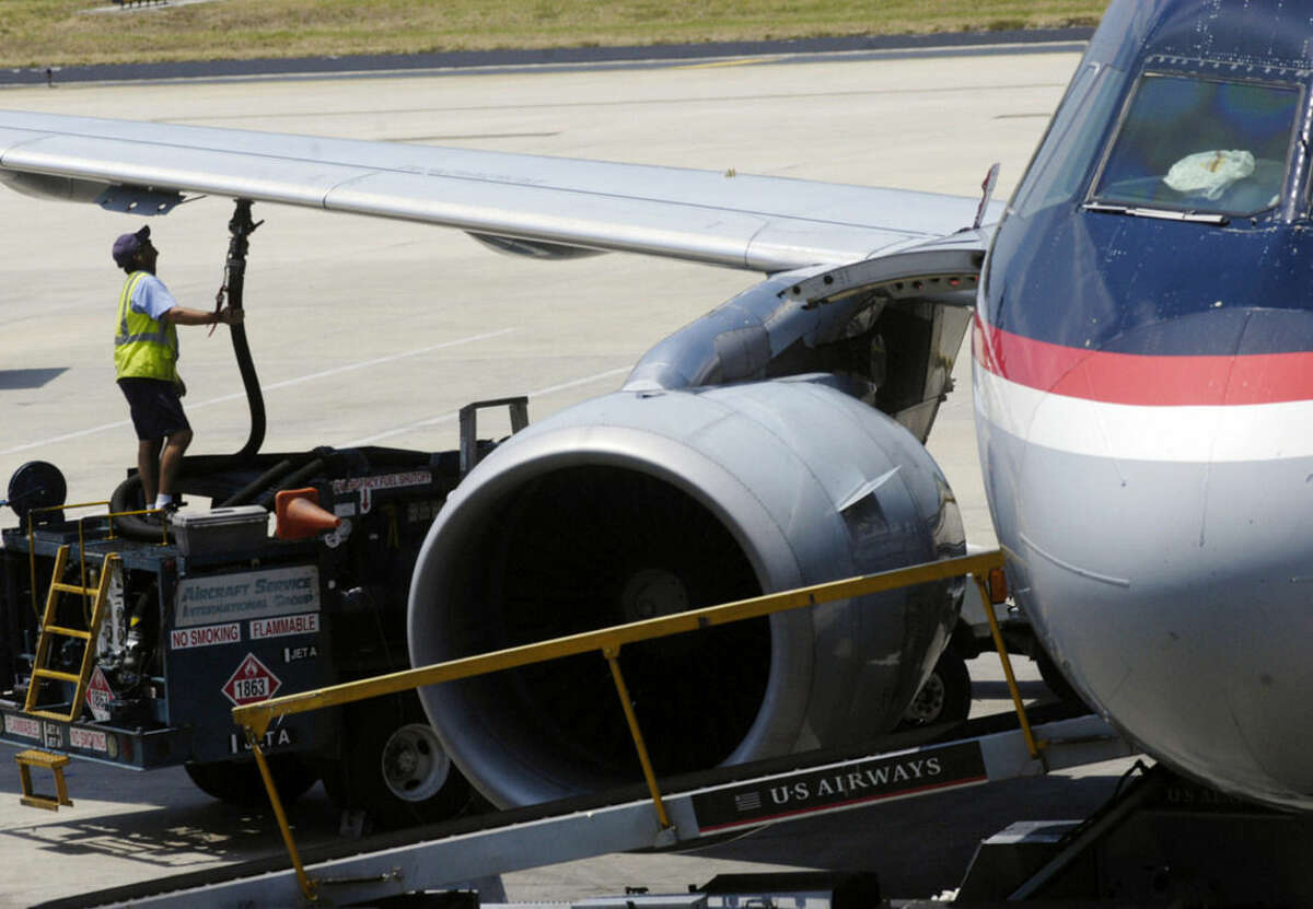 FILE - In this June 12, 2008 file photo, a worker hooks up a fuel hose to an airplane at Tampa International Airport in Tampa, Fla. In the 12 months ended in September 2014, U.S. airlines saved $1.6 billion on jet fuel _ their largest expense. In the first three quarters of 2014, airlines posted a 5.7 percent profit margin, robust for the industry. (AP Photo/Brian McDermott, File)
