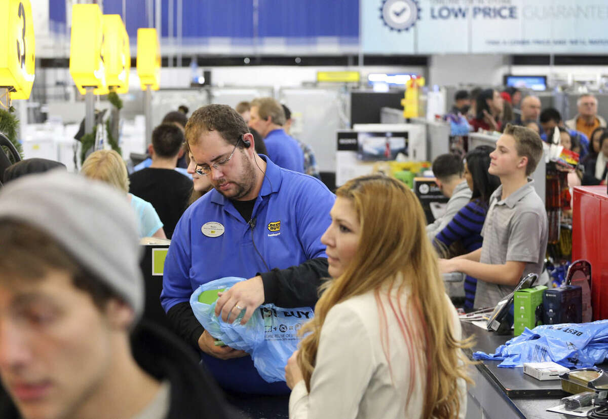 Cashier Ryan Gray helps customers during a Thanksgiving day sale at a Best Buy store in Broomfield, Colo., on Thursday, Nov. 27, 2014. (AP Photo/Brennan Linsley)