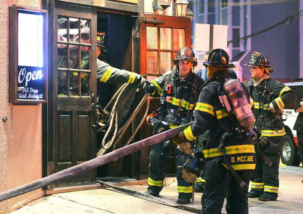 Hour Photo/Alex von Kleydorff Norwalk Firefighters get a hose inside B.J. Ryan's on Main St. Monday evening in response to a fire in the kitchen of the restaurant