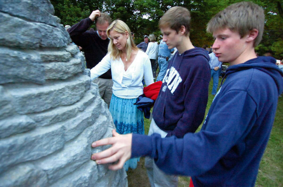From left to right: Charlie Sandor and Alex Mirabile remember friend Nick Parisot during a memorial in 2013 near the Stone Cairn sculpture Father Rick Parisot built in a corner of a field at Millstone Farm in Wilton 