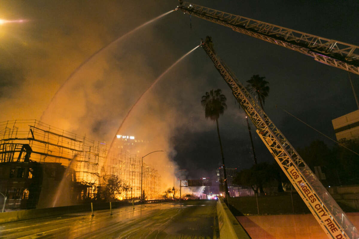 Los Angeles County firefighters battle a fire at an apartment building under construction next to the Harbor CA-110 Freeway in Los Angeles, early Monday, Dec. 8, 2014. The building was not occupied, the Los Angeles Fire Department reported. (AP Photo/Damian Dovarganes)