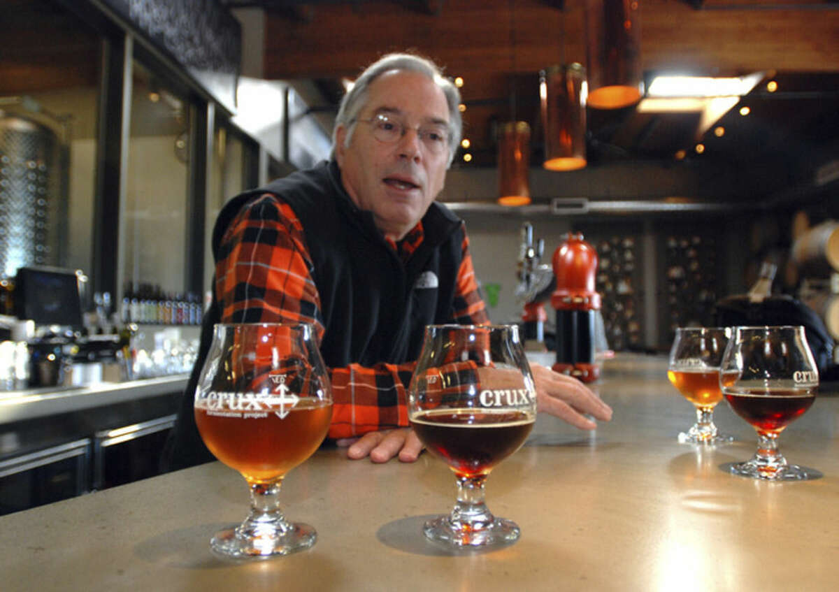 In this Nov. 18, 2014 photo, brewmaster Larry Sidor discusses some of his creations at Crux Fermentation Project's brew pub in Bend, Ore. Sidor has been one of the brewers pushing the envelope on beer in Bend, which has seen an explosion of new breweries as the town has grown. One, 10 Barrel Brewing Co., recently announced it is being bought by Anheuser-Busch InBev, the world's largest brewer. Sidor worries that major corporations buying craft brewers will ultimately lead to the "commoditization" of craft beer. (AP Photo/Jeff Barnard)