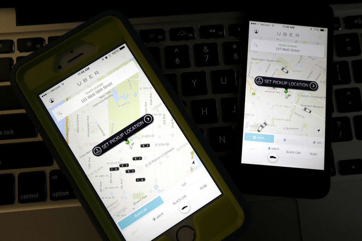 FILE - This Friday, Nov. 21, 2014 file photo taken in Newark, N.J., shows smart phones displaying Uber car availability in New York. The ride-hailing app expects this New Year’s Eve to be its busiest night ever. Due to such high demand, and because it can, Uber is bringing back its surge pricing, a boon to drivers and a bane to passengers. Fares can increase by as much as sevenfold during the busiest time, which Uber says will be between 12:30 a.m. and 2:30 a.m.(AP Photo/Julio Cortez, File)