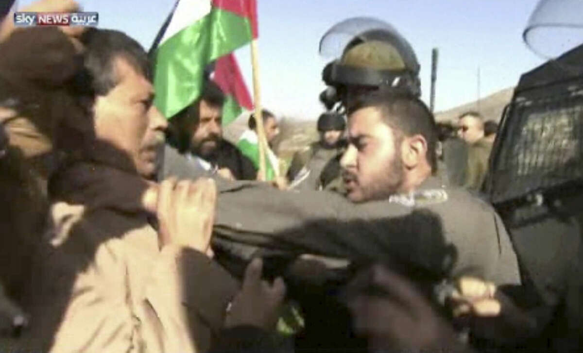 In this image taken from video, an Israeli officer, right, grabs the throat of Palestinian Cabinet member Ziad Abu Ain during a protest in the West Bank city of Turmus Aya, Wednesday, Dec. 10, 2014. Abu Ain died Wednesday following the scuffle with Israeli troops, quickly stirring Palestinian anger at a time of badly strained relations with Israel. An autopsy has yet to determine what killed Abu Ain, but Palestinian President Mahmoud Abbas called him the victim of a "clear crime" and a "barbaric act." He decreed three days of mourning for the minister, whose portfolio included organizing protests against Israeli settlements and the West Bank separation barrier. (AP Photo/Sky News Arabia via AP Video)