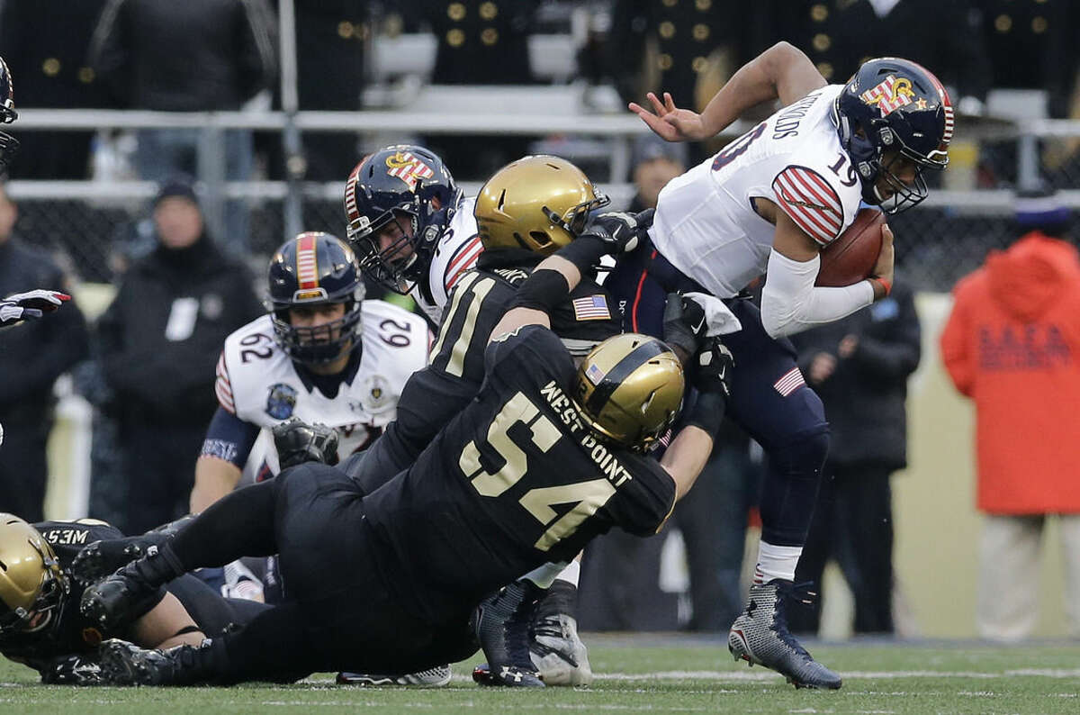 Navy quarterback Keenan Reynolds, right, is tackled for a loss of yards by Army defensive lineman Joe Drummond (54) and linebacker Andrew King in the first half of an NCAA college football game, Saturday, Dec. 13, 2014, in Baltimore. (AP Photo/Patrick Semansky)