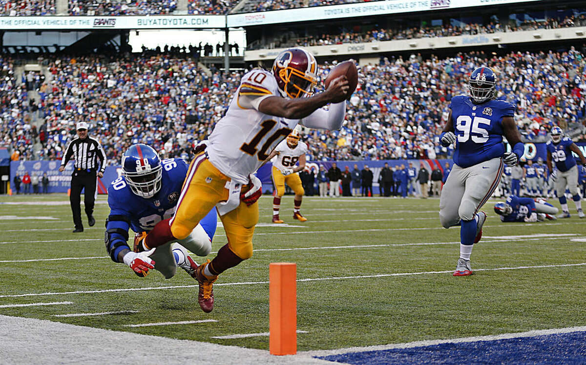 Washington Redskins quarterback Robert Griffin III (10) leaps for the goal line attempting to score a touchdown against New York Giants defensive end Jason Pierre-Paul (90) during the second quarter of an NFL football game, Sunday, Dec. 14, 2014, in East Rutherford, N.J. (AP Photo/Julio Cortez)