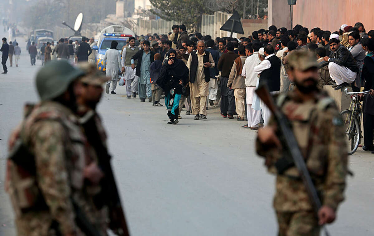 People wait for their kids outside a school attacked by the Taliban in Peshawar, Pakistan, Tuesday, Tuesday, Dec. 16, 2014. Taliban gunmen stormed a military-run school in the northwestern Pakistani city of Peshawar on Tuesday, killing and wounding scores, officials said, in the highest-profile militant attack to hit the troubled region in months. (AP Photo/B.K. Bangash)