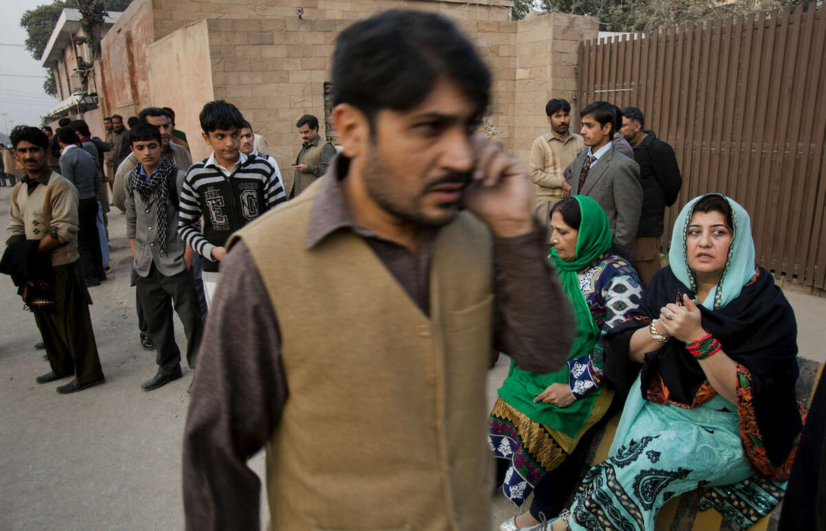 People wait for their children outside a school attacked by the Taliban in Peshawar, Pakistan, Tuesday, Dec. 16, 2014. Taliban gunmen stormed a military-run school in the northwestern Pakistani city of Peshawar on Tuesday, killing and wounding scores, officials said, in the highest-profile militant attack to hit the troubled region in months. (AP Photo/B.K. Bangash)