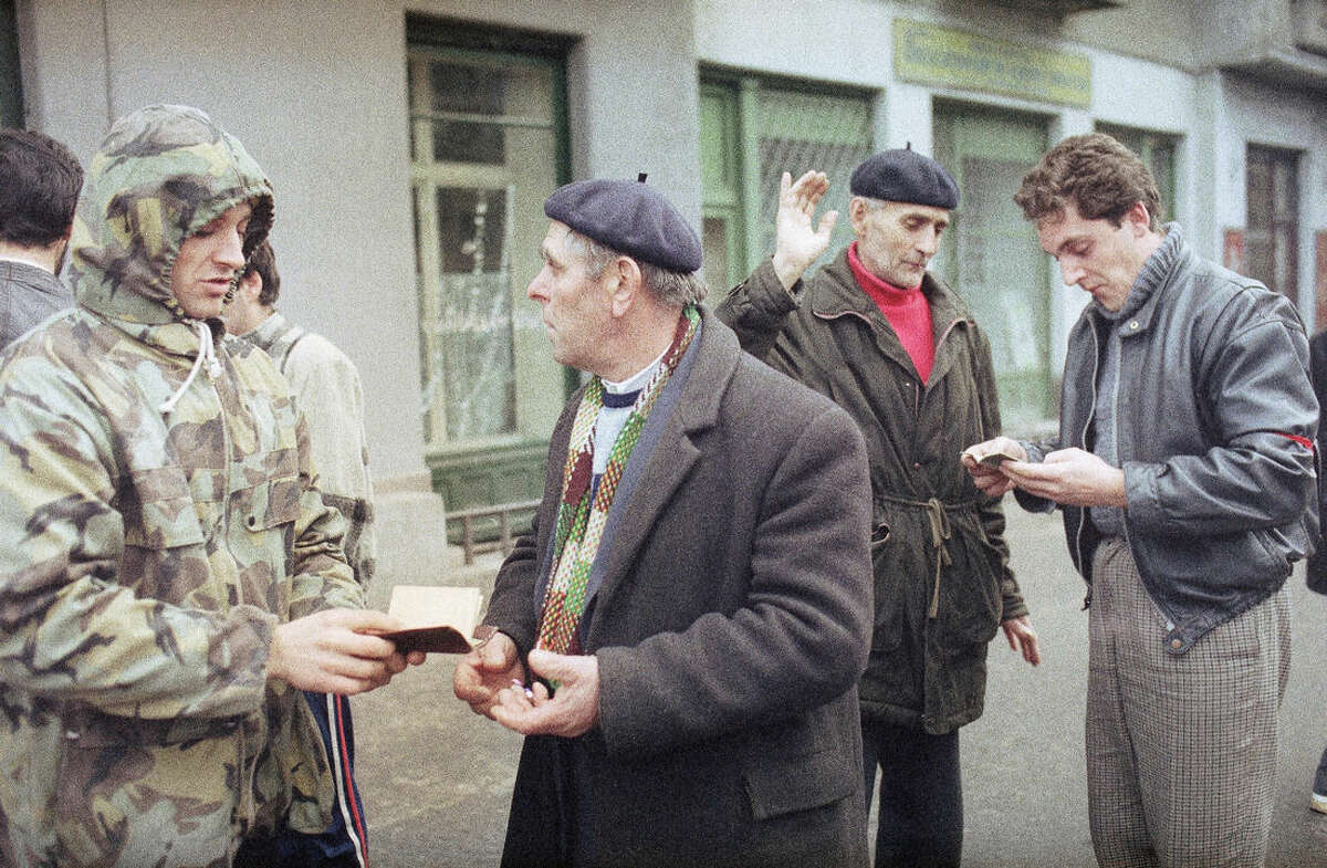FILE - This is a Dec. 23, 1989 file photo of civilian guards checking the documents of passers-by on the streets of Timisoara, Romania, in search for the plain clothes pro-Ceausescu secret police members. More than 5,000 people were killed in Timisoara this week. Twenty-five years ago the people rose up against Romanian dictator Nicolae Ceausescu, executed him and set the country on a path to democracy. (AP Photo/Dusan Vranic, File)