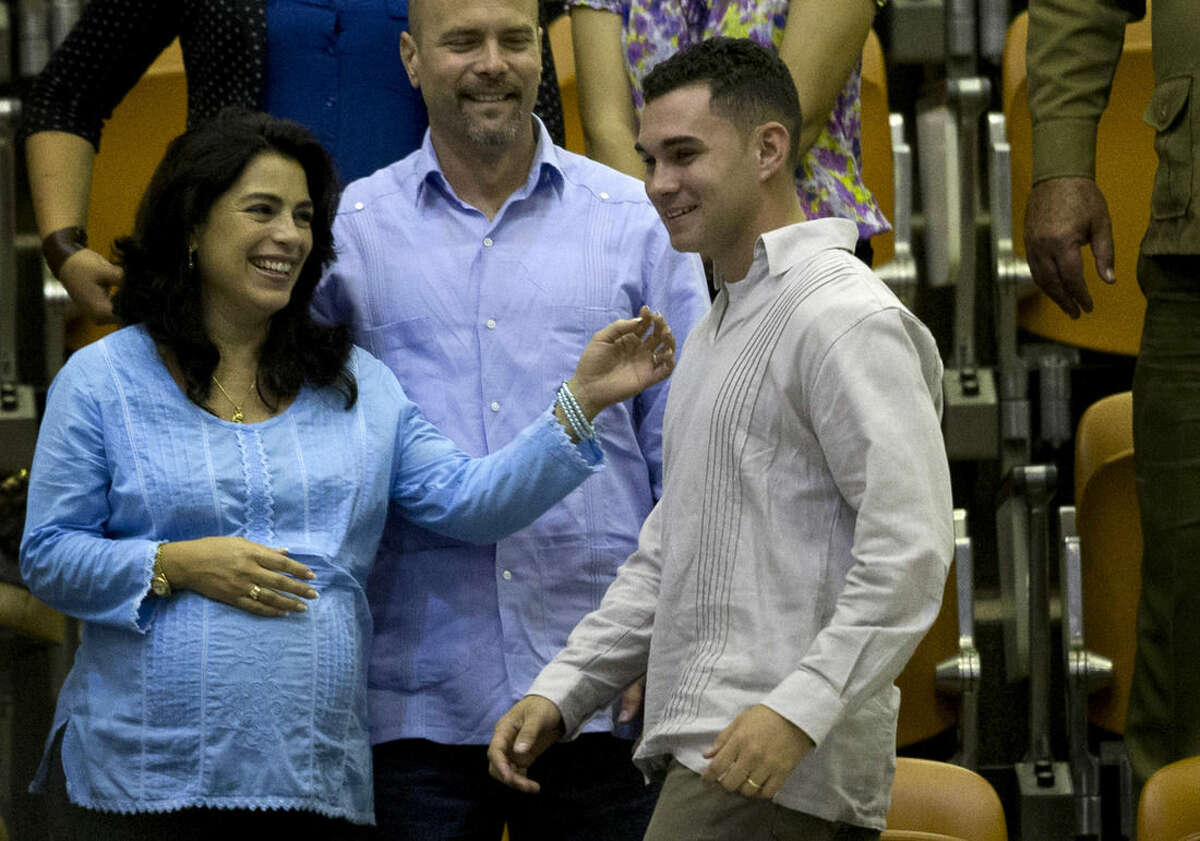 Elian Gonzalez, the young Cuban rafter who was at the center of a bitter custody battle in 2000 between relatives in Miami and his father in Cuba, attends the closing ceremony of the legislative session at the National Assembly in Havana, Cuba, Saturday, Dec. 20, 2014. Behind stands Gerardo Hernandez, one of the last imprisoned members of the "Cuban Five" spy ring who were freed this week. (AP Photo/Ramon Espinosa)