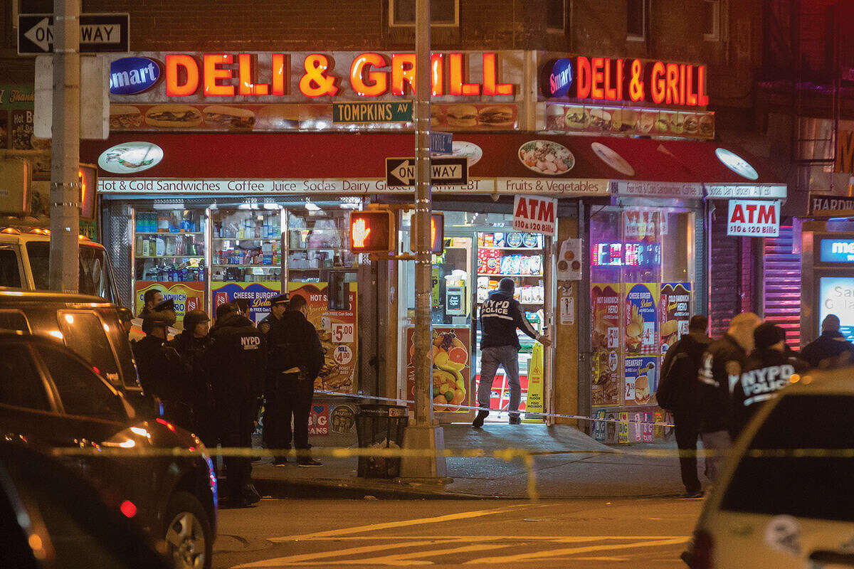 Investigators work in the area where two NYPD officers were shot in the Bedford-Stuyvesant neighborhood of the Brooklyn borough of New York on Saturday, Dec. 20, 2014. Police said an armed man walked up to two officers sitting inside a patrol car and opened fire before running into a nearby subway station and committing suicide. Both police officers were killed. (AP Photo/John Minchillo)