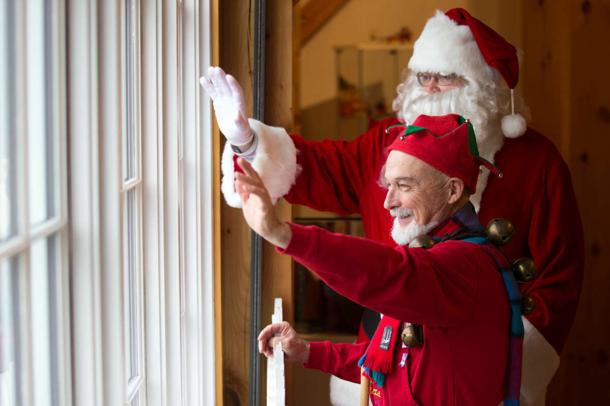 Hour photo/Chris Palermo. Roy Marsh as an elf and Bill Brady as Santa wave goodbye to children at the Weston Historical Society Sunday afternoon.