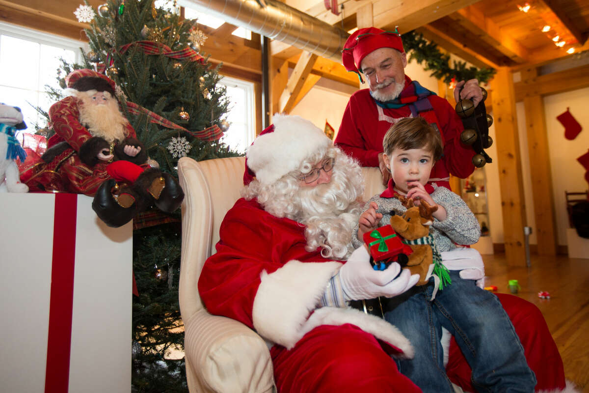 Hour photo/Chris Palermo. Grant Failla, 2, sits with Santa and one of his elves at the Weston Historical Society Sunday afternoon.
