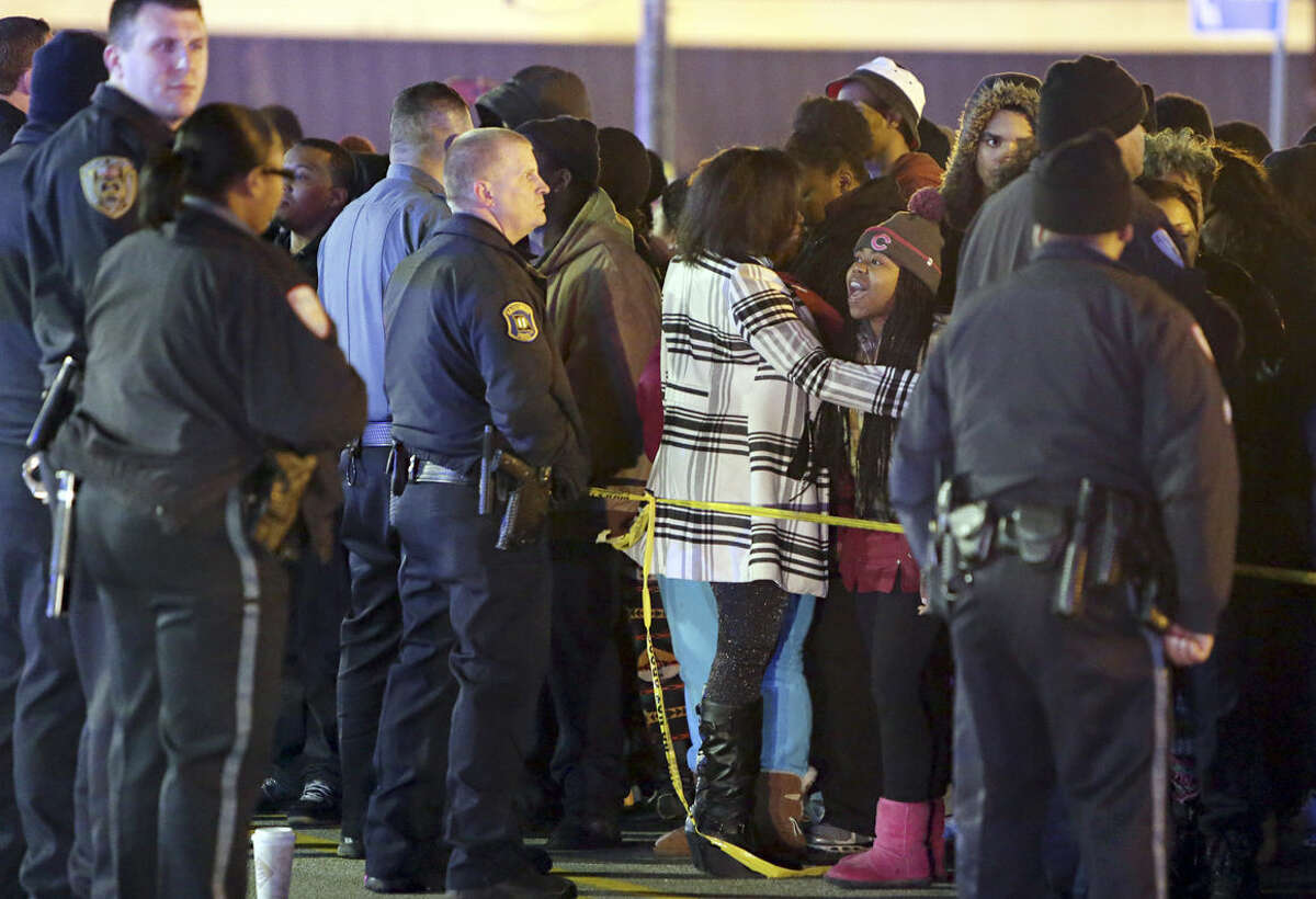 Police hold back a crowd at the perimeter of a scene on Wednesday, Dec. 24, 2014, following a shooting Tuesday at a gas station in Berkeley, Mo. St. Louis County police say a man who pulled a gun and pointed it at an officer has been killed. (AP Photo/St. Louis Post-Dispatch, David Carson)