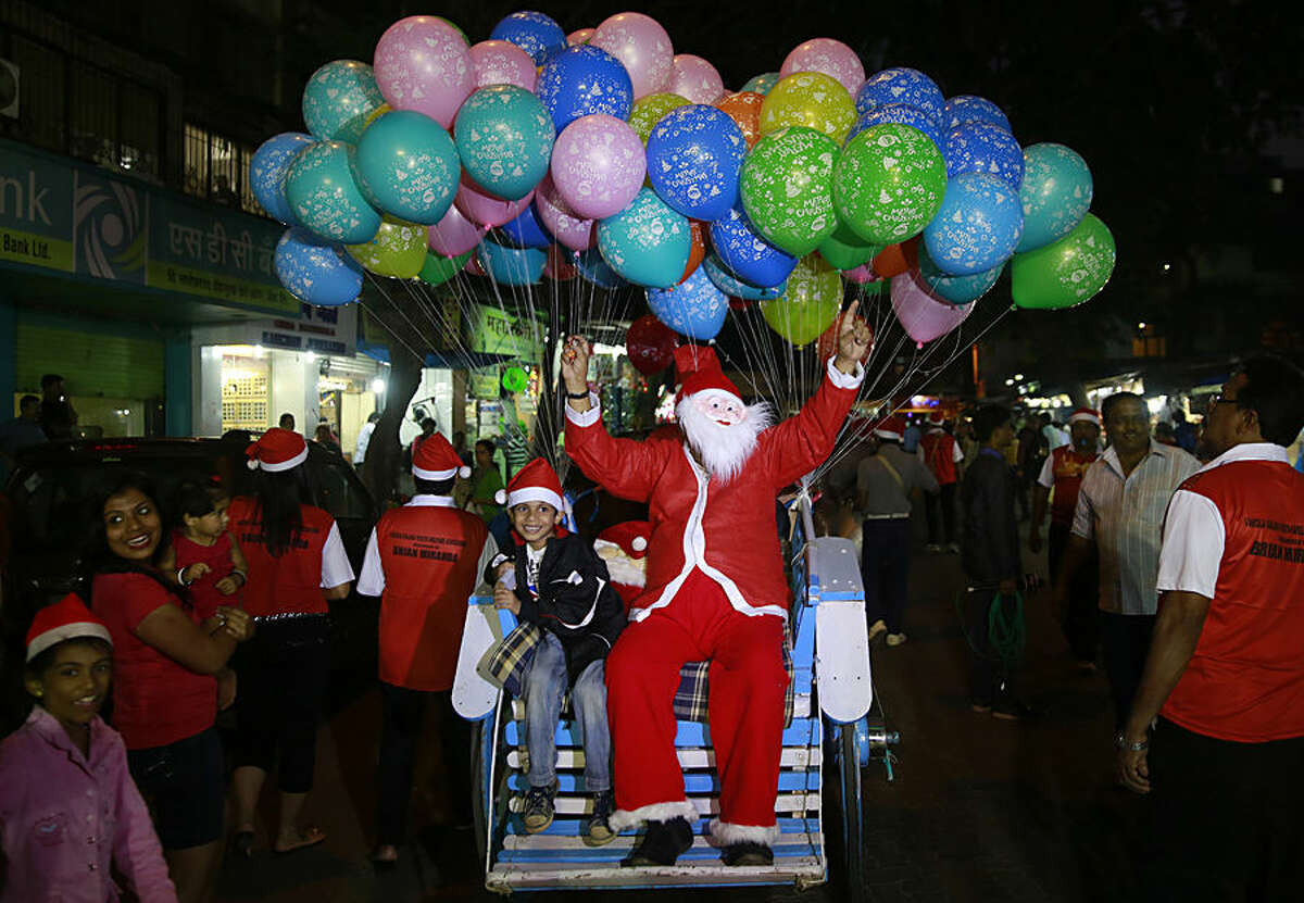A man dressed as Santa Claus sits on a horse cart with a child during a Christmas carnival in Mumbai, India, Tuesday, Dec 23, 2014. (AP Photo/Rafiq Maqbool)--