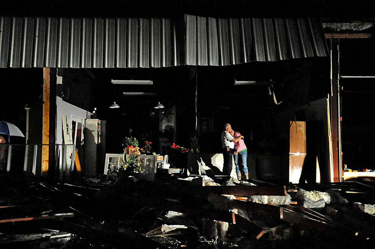 Jeff and Melissa McKenzie embrace in the ruins of their florist and gift shop store in Columbia, Miss., after a tornado ripped through the city Tuesday, Dec. 23, 2014. According to Marion County Emergency Management the tornado touched down around 2:30 p.m. Tuesday. (AP Photo/The Hattiesburg American, Eli Baylis)