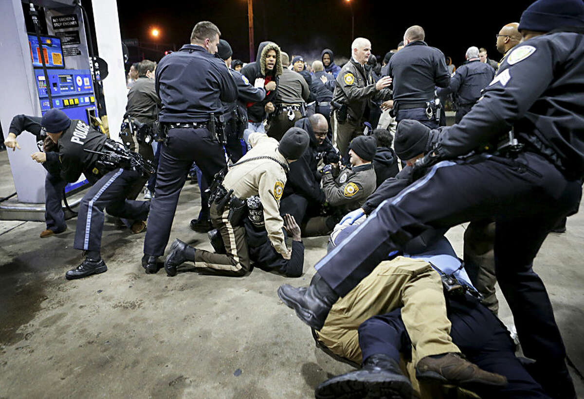 Police try to control a crowd Wednesday, Dec. 24, 2014, on the lot of a gas station following a shooting Tuesday in Berkeley, Mo. St. Louis County police say a man who pulled a gun and pointed it at an officer has been killed. (AP Photo/St. Louis Post-Dispatch, David Carson)