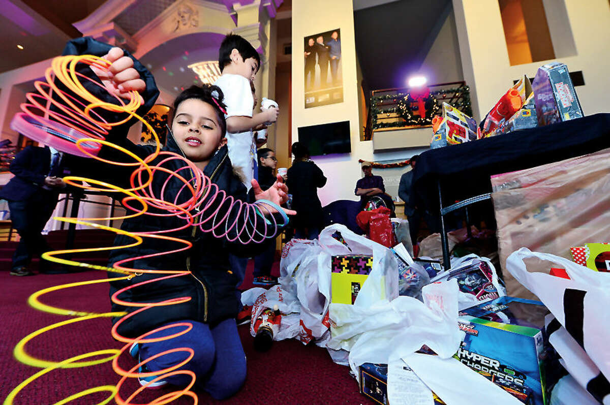 Hour photo / Erik Trautmann Nilah Palermo, 5, plays with a new slinky at the Stamford Media Center as NBCUniversal executives and employees prepare to load up a van full of toys for distribution to children at the Boys & Girls Club of Stamford. The toys were donated by NBCUniversal employees as part of the company’s annual Holiday Toy Drive.