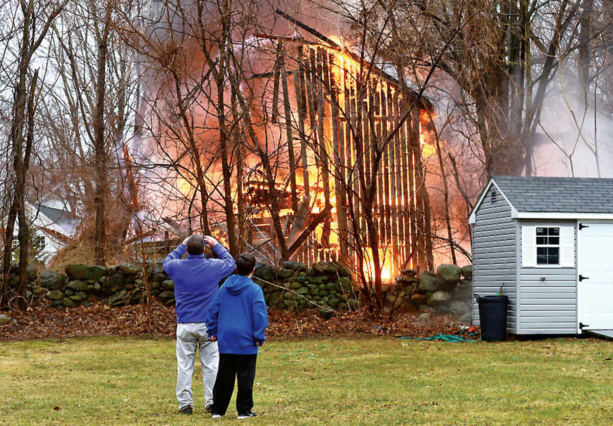 Hour photo / Erik Trautmann Jerry Quinn and his son Connor watch as a barn at 41 Fox Run Rd in Norwalk is destroyed by fire Saturday afternoon.
