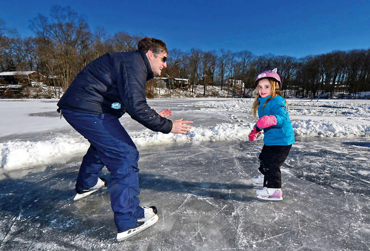 Hour photo / Erik Trautmann Frank Robertson teaches his daughter Ruby, 4, how to skate at Woods Pond Saturday.