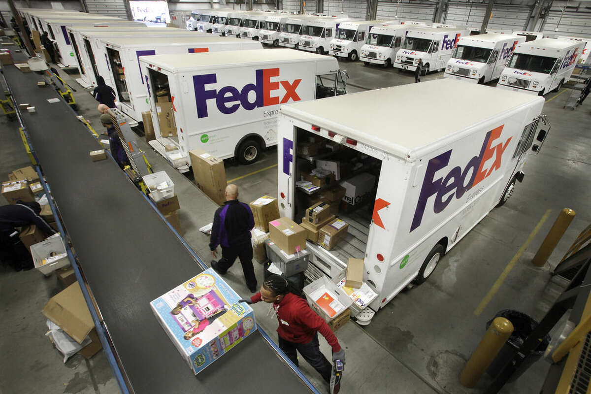 FILE - In this Dec. 15, 2014 file photo, FedEx employees pull boxes from a conveyor belt and fill their trucks for deliveries at a FedEx sorting facility in the Bronx borough of New York. After FedEx and UPS failed to deliver some presents in time for Christmas last year, the two package carriers seem to have improved their performance this holiday season. But shipments from retailers weren’t without hiccups. (AP Photo/Mark Lennihan, File)
