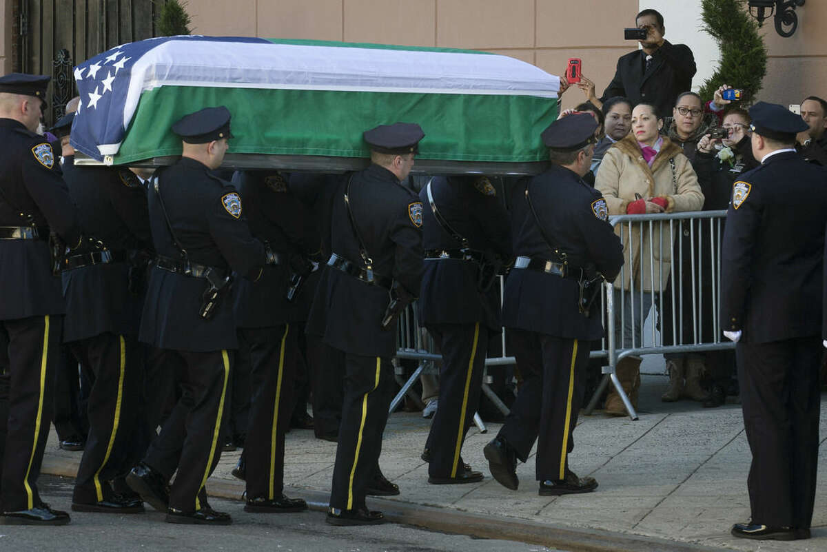 The casket of New York Police Department officer Rafael Ramos arrives to his wake at Christ Tabernacle Church in the Glendale section of Queens, where he was a member, Friday, Dec. 26, 2014, in New York. Ramos was killed Dec. 20 along with his partner, Officer Wenjian Liu, as they sat in their patrol car on a Brooklyn street. The shooter, Ismaaiyl Brinsley, later killed himself. (AP Photo/John Minchillo)