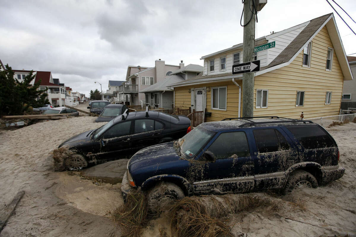 FILE - In this Oct. 30, 2012 file photo, cars lifted by floodwater are mired in several feet of sand in the aftermath of Superstorm Sandy, in Long Beach, N.Y. Lawyers representing about 1,500 homeowners are trying to prove that some engineering firms hired to inspect the damage issued bogus reports to give skeptical insurers ammunition to deny claims. (AP Photo/Jason DeCrow, File)