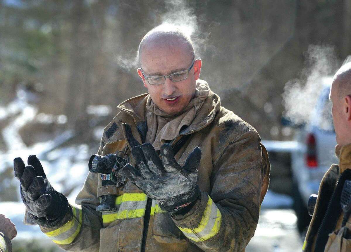 Hour Photo/Alex von Kleydorff Wilton Firefighter Mike Blatchley check his equipment as frigid temperatures cause steam to rise from his head after removing his helmet during a house fire in Wilton on Tuesday