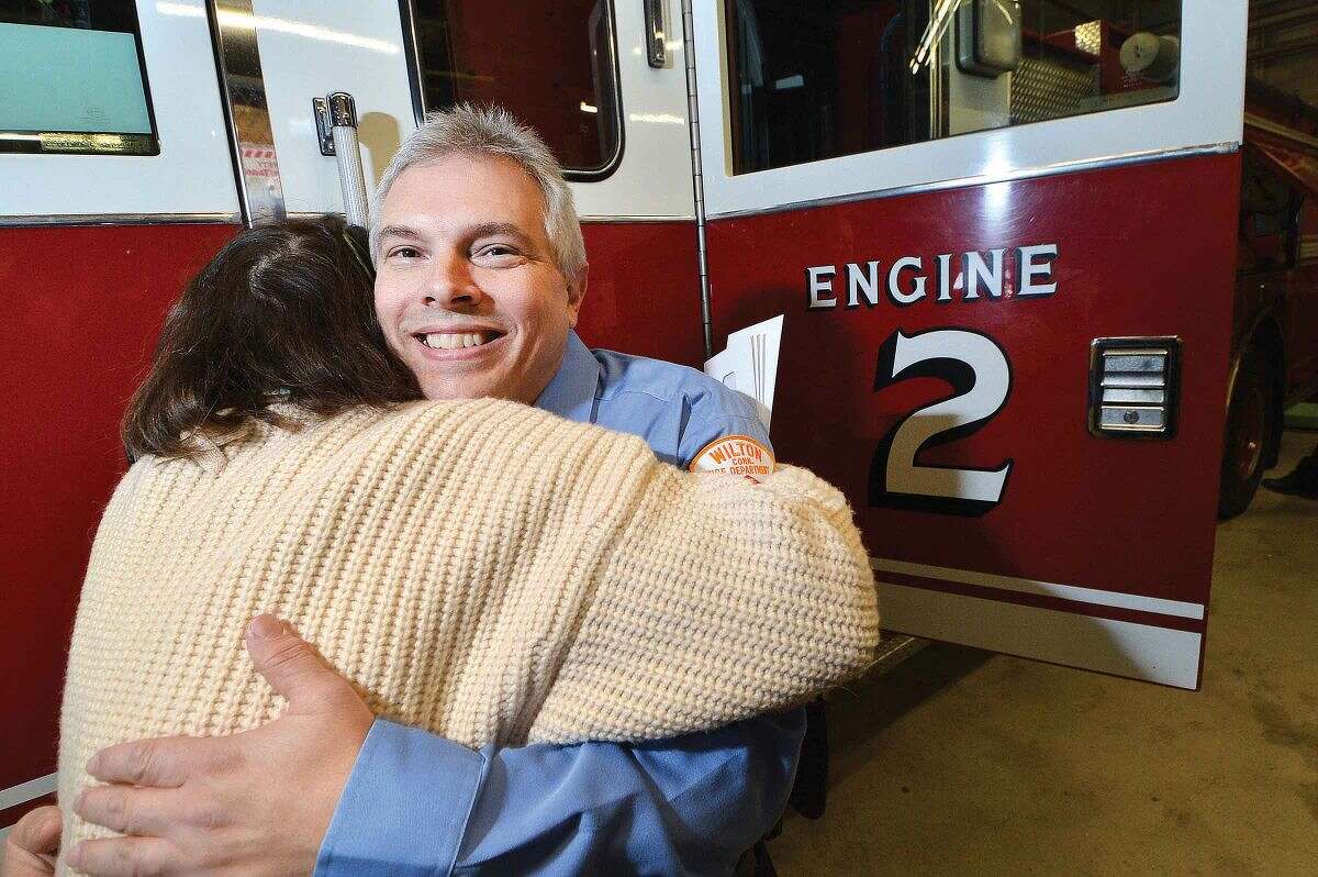 Hour Photo/Alex von Kleydorff Wilton Firefighter Tom Coon gets a hug from Fire Department Administrator Kathy Horn as she wishes him well on his retirement after 33 years of service with the department.