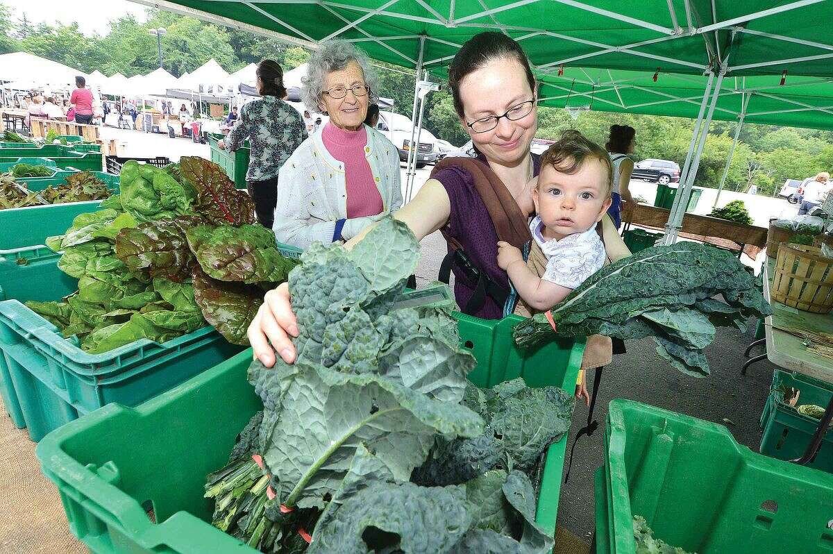 Hour Photo/Alex von Kleydorff 9 month old Justas Kere hangs on mom Giedre as she buys some fresh picked Lacinato Kale from Fort Hill Farm in New Milford during Thursday's farmers Market in Westport