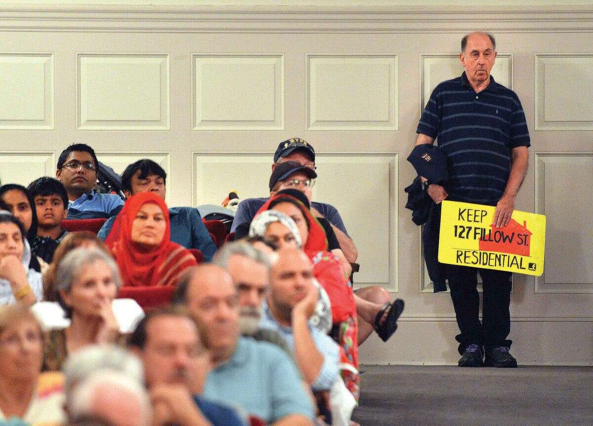 Hour Photo/Alex von Kleydorff A man holds a sign in the back of the Concert Hall during the Norwalk Zoning Commission Public Hearing regarding the proposed Al Madany Islamic Center