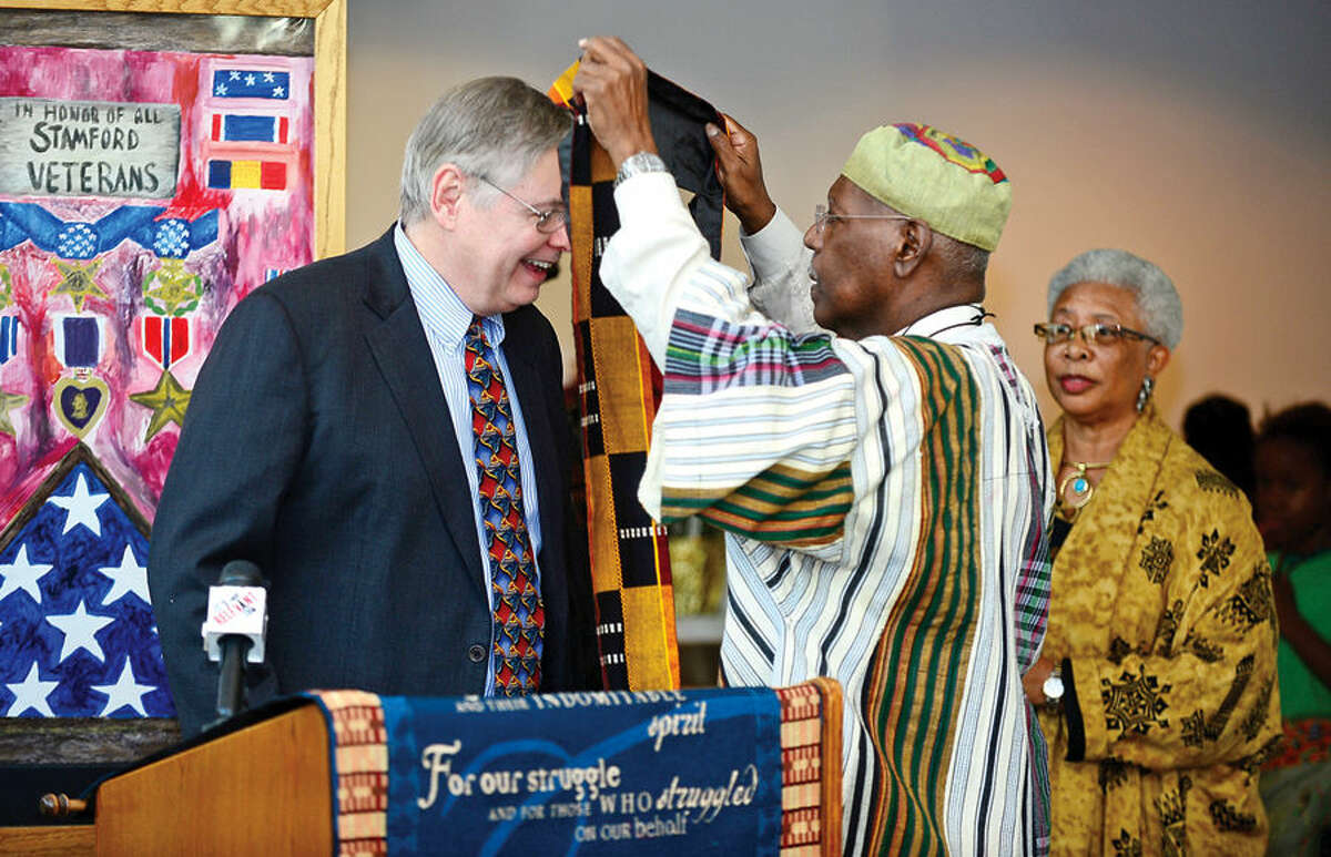 Hour photo / Erik Trautmann Stamford mayor david martin is presented with a traditional african Kente stole from Phillip McKain during the city’s 20th annual Kwanzaa celebration Tuesday at the Stamford Government Center.