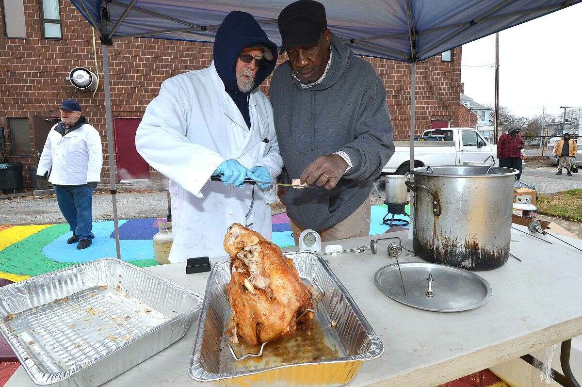 Hour Photo/Alex von Kleydorff Ernie Dumas and Peter Havens check a turkey just pulled from the deep fryer during South Norwalk Community Organization Thanksgiving dinner and coat giveaway on Thursday