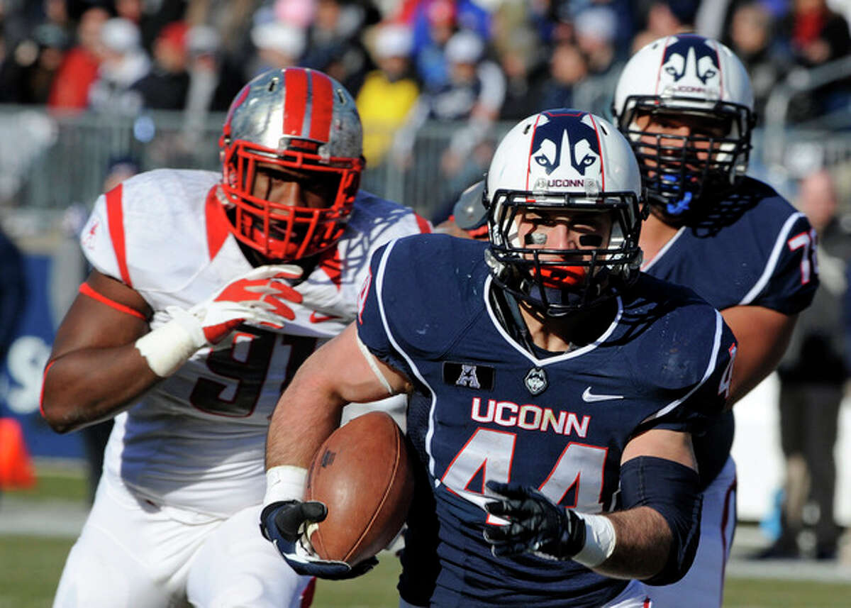 Connecticut running back Max DeLorenzo (44) runs for a touchdown while being pursued by Rutgers defensive lineman Darius Hamilton (91 left, during the first half an NCAA college football game in East Hartford, Conn., on Saturday, Nov. 30, 2013. (AP Photo/Fred Beckham)