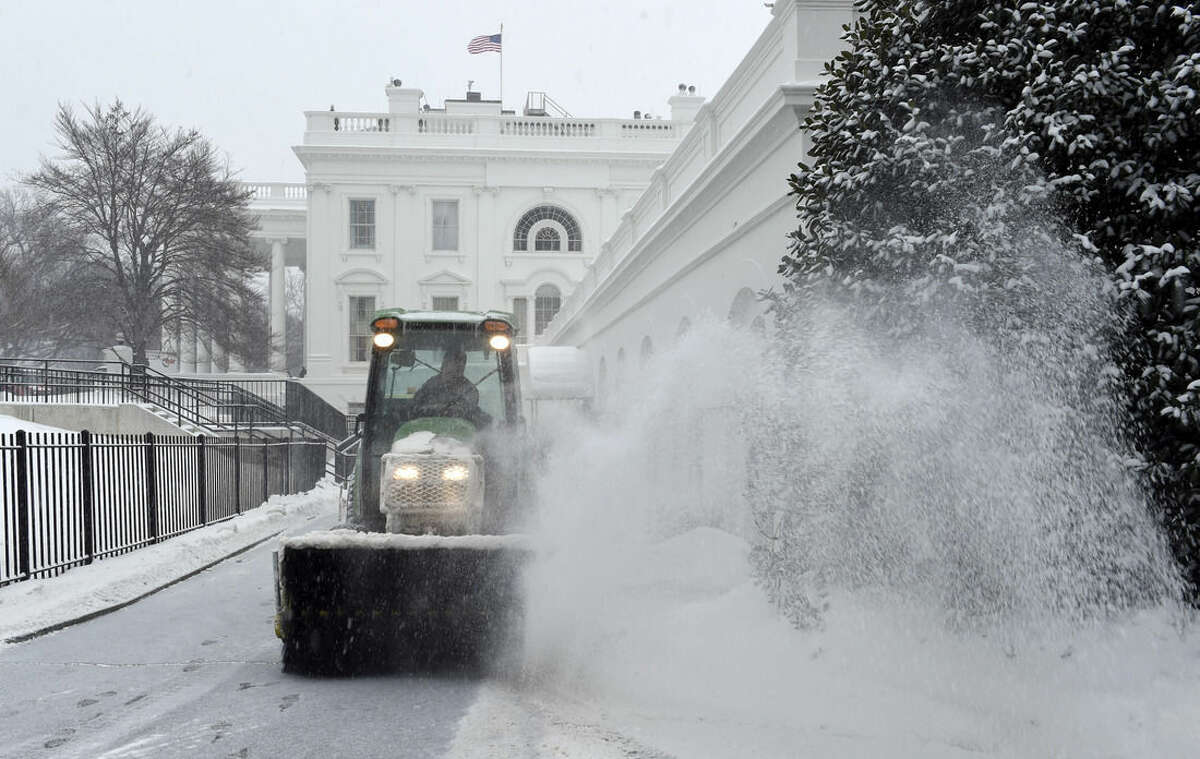 Snow is cleared on the North side of the White House in Washington, Saturday, Feb. 21, 2015. The National Weather Service is calling for 3 to 6 inches of snow and then a trace to a small amount of ice in the area. The cold ground is allowing snow to stick faster, making it difficult for road crews to keep up. (AP Photo/Susan Walsh)