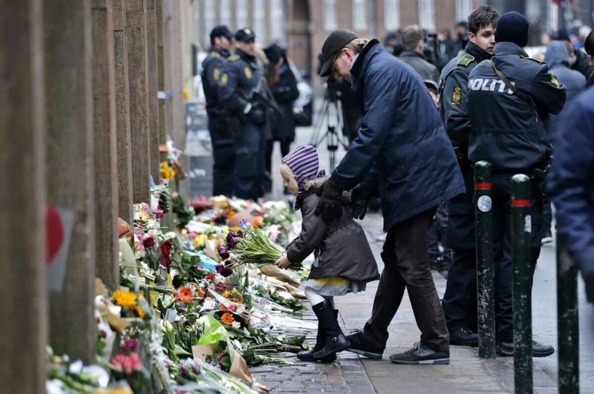 People laying flowers outside a synagogue where an attack took place, in Copenhagen, Sunday, Feb. 15, 2015. Danish police shot and killed a man early Sunday suspected of carrying out shooting attacks at a free speech event and then at a Copenhagen synagogue, killing a Danish documentary filmmaker and a member of the Scandinavian country's Jewish community. Five police officers were also wounded in the attacks. (AP Photo/Polfoto, Jens Dresling) DENMARK OUT