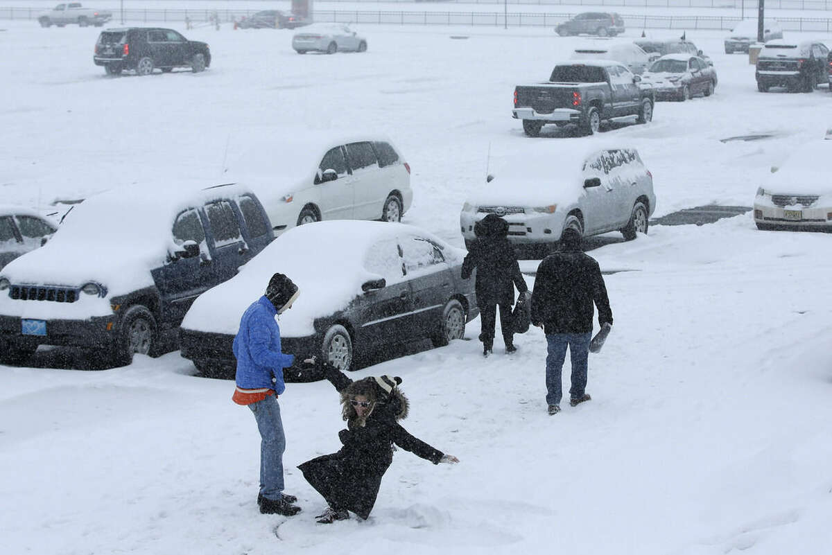 A woman is helped up after making a snow angel in a parking lot outside the Wells Fargo Center during a winter storm after an NHL hockey game between the Philadelphia Flyers and the Nashville Predators, Saturday, Feb. 21, 2015, in Philadelphia. (AP Photo/Matt Slocum)