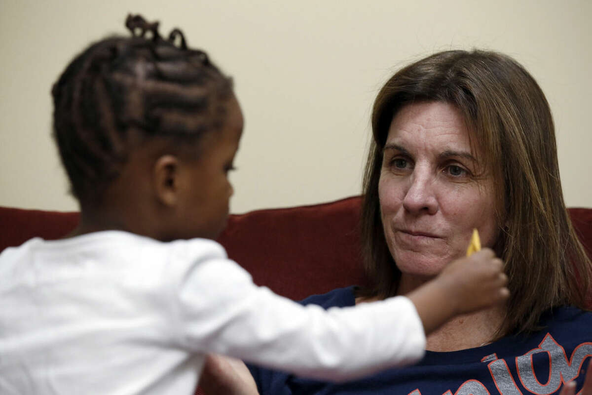In this Jan. 27, 2015, photo, Ngoty plays with her adopted mother, Virginia women's basketball coach Joanne Boyle, at Bridge Outreach Church in Charlottesville, Va. Boyle had known for decades that she wanted to adopt a child, yet it would not be easy. She took 12 trips to Senegal over nearly three years, 14 in all. (AP Photo/Alex Brandon)