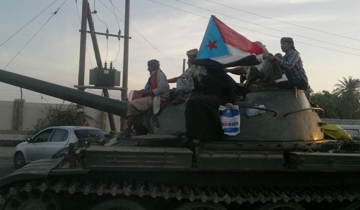 Militiamen loyal to President Abed Rabbo Mansour Hadi ride on a tank on a street in Aden, Yemen, Thursday, March 19, 2015. A woman on the tank holds a representation of the old South Yemen flag that was used when southern Yemen was an independent state until 1990. Forces loyal to Yemen's former President Ali Abdullah Saleh stormed the international airport in the southern port city of Aden on Thursday, triggering an intense, hours-long gunbattle with the forces of the current President Hadi that intensified a monthslong struggle for power threatening to fragment the nation. (AP Photo/Hamza Hendawi)