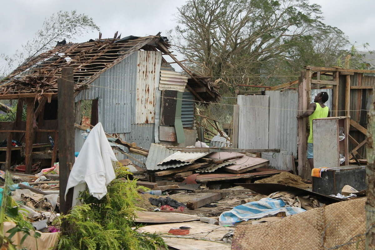 In this Tuesday, March 17, 2014, photo provided by UNICEF Pacific, a man looks into the remains of a house in the wake of Cyclone Pam. When Cyclone Pam ripped across the tiny South Pacific island nation of Vanuatu, there were fears its monstrous winds could kill thousands. But as aid workers finally reached the archipelago's hard-hit outer islands on Wednesday, it appeared that residents' familiarity with disasters and careful planning had spared the lives of most. (AP Photo/UNICEF Pacific) EDITORIAL USE ONLY, NO SALES