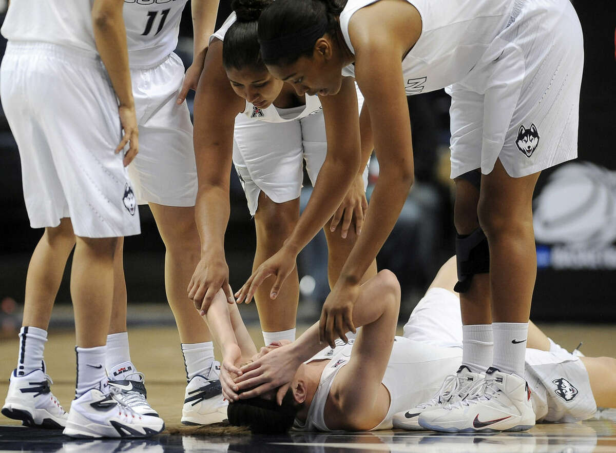 Connecticut’s Kaleena Mosqueda-Lewis, top center, with Morgan Tuck, top right, reach down to check on teammate Breanna Stewart, bottom, after Stewart collided with another player during the first half of a women's college basketball game against Rutgers in the second round of the NCAA tournament, Monday, March 23, 2015, in Storrs, Conn. (AP Photo/Jessica Hill)