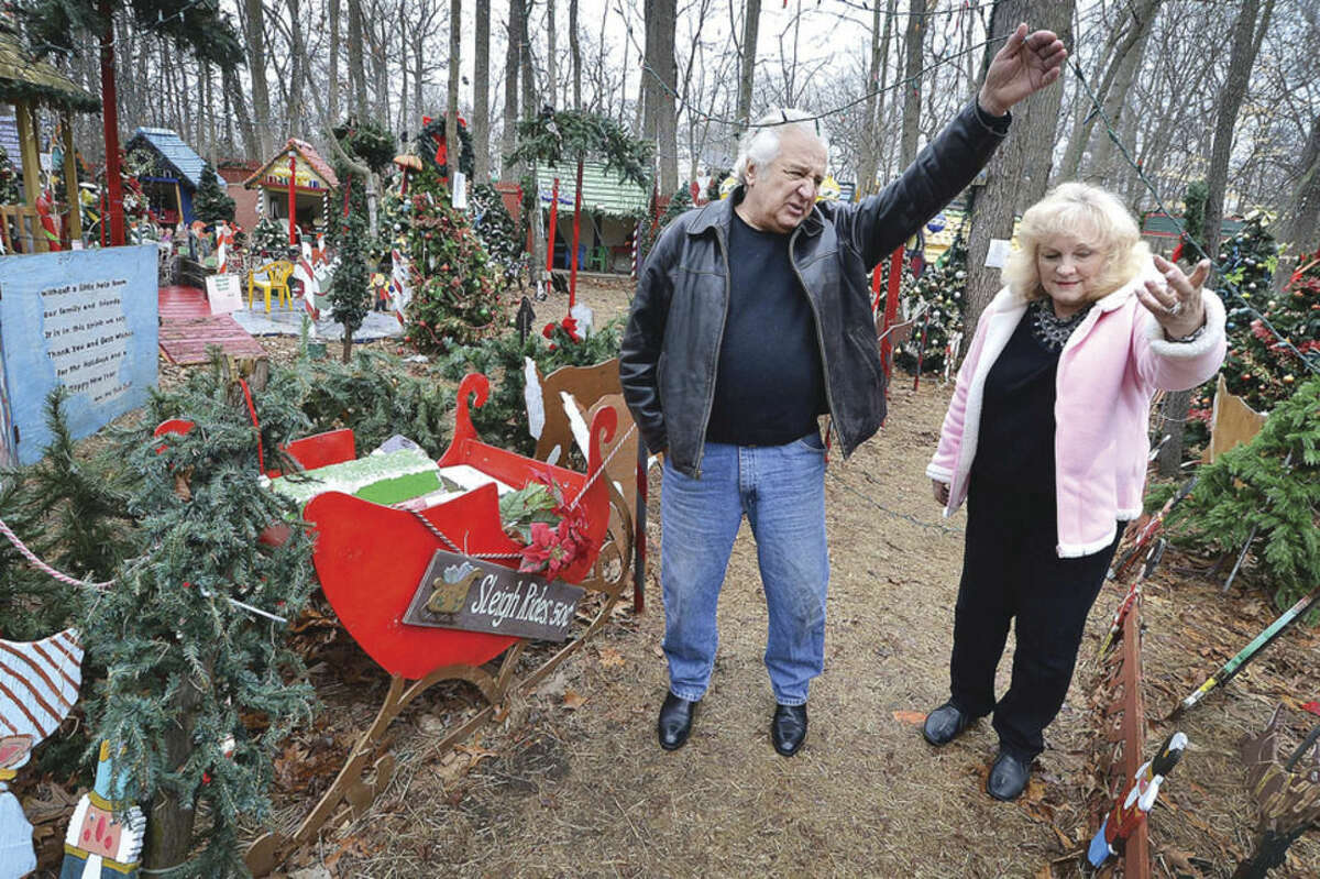 Hour Photo/Alex von Kleydorff Rick holds up a string of lights so his wife Joan can pass under, during a walk through of their Christmas display on Tuesday. Rick and Joan Setti will hold a tag sale to sell the items they have built and displayed over the last 26 Holiday's at their Norwalk home