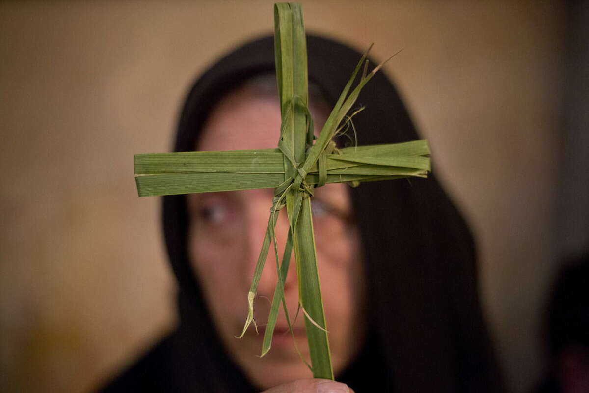 A Greek Orthodox woman holds a palm fond Greek in the Church of the Holy Sepulcher, traditionally believed by many to be the site of the crucifixion and burial of Jesus Christ during Orthodox Palm Sunday, in Jerusalem, Sunday, April 5, 2015. Christians in the Holy Land and across the world are celebrating Easter, commemorating the day followers believe Jesus was resurrected in Jerusalem 2,000 years ago. (AP Photo/Ariel Schalit)