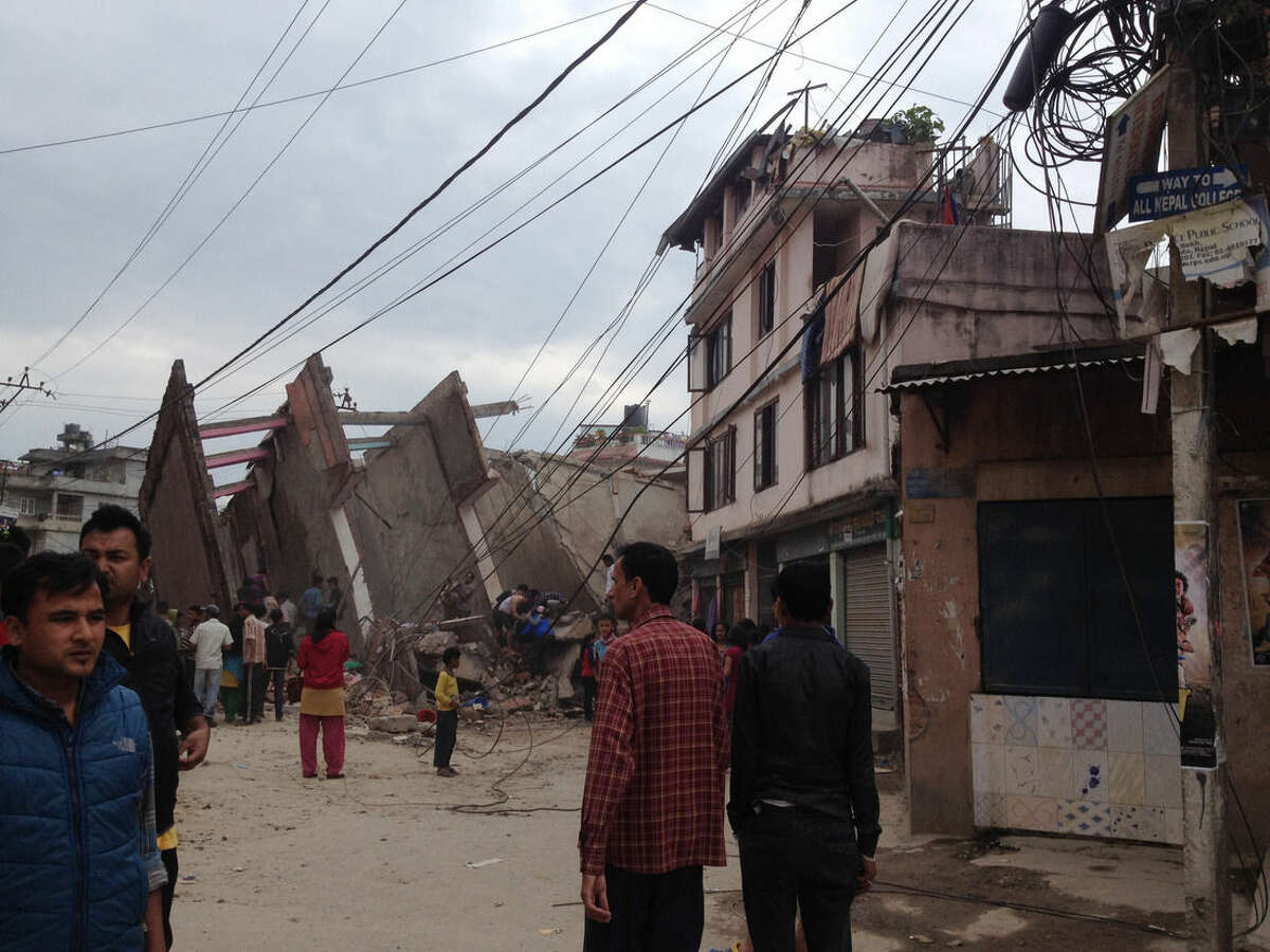 In this photo provided by Guna Raj Luitel, people walk next to ruble after an earthquake in Kathmandu, Nepal, Saturday, April 25, 2015. A powerful earthquake shook Nepal's capital and the densely populated Kathmandu Valley before noon Saturday, collapsing houses, leveling centuries-old temples and cutting open roads in the worst temblor in the Himalayan nation in over 80 years. (Guna Raj Luitel via AP)