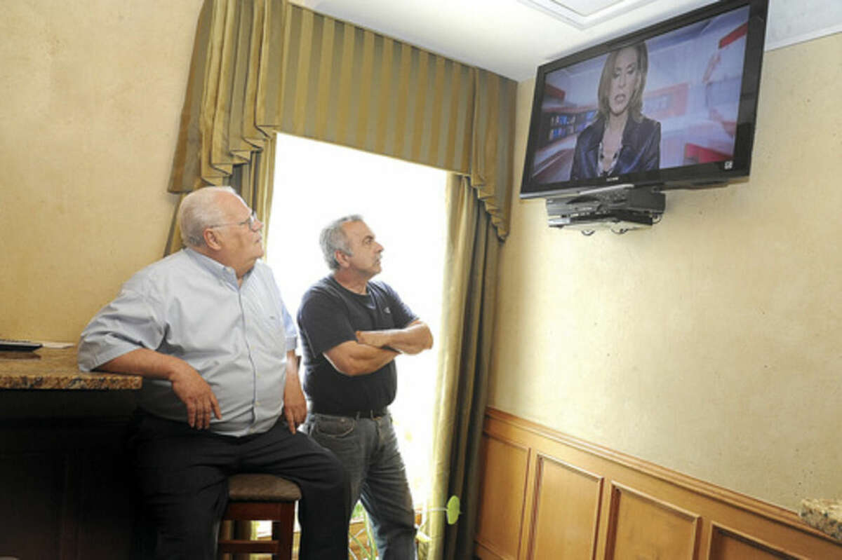Co-owner of the Norwalk Inn and Conference Center Chris Handrinos with his friend (Gus) Konstantinos Kazantzidis watch a news program from Athens Monday afternoon concerned about the recent economy issues in Greece. Hour photo/Matthew Vinci