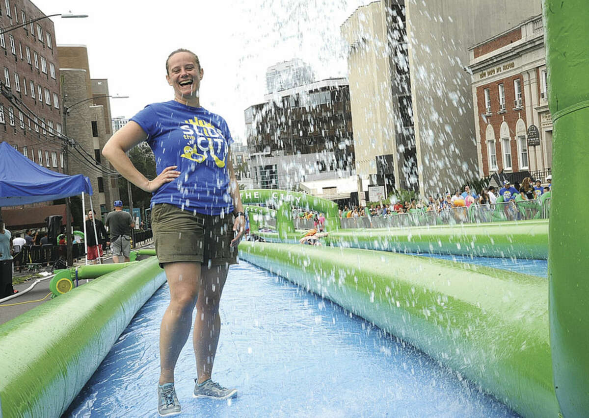 Volunteer Charity Miller gets wet Sunday on the giant water slide at the Slide City event held in downtown Stamford. Hour photo/Matthew Vinci