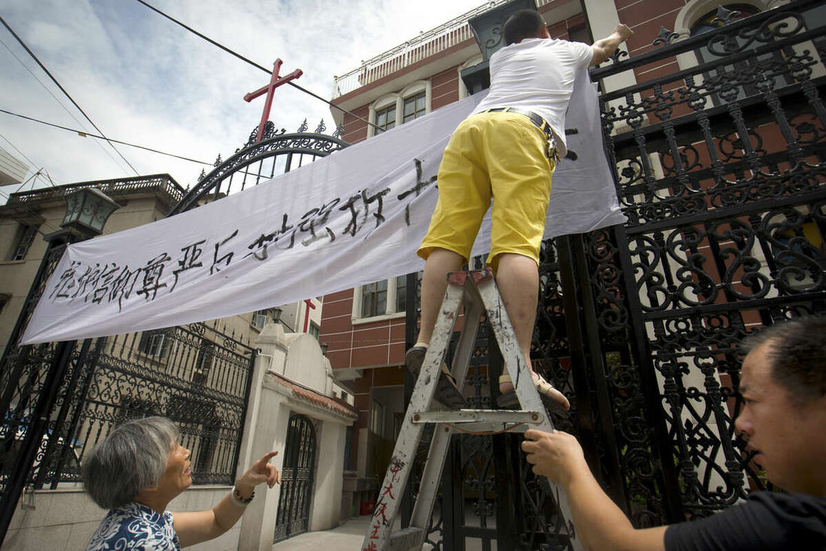 In this July 30, 2015 photo, church members put up a banner reading "Safeguard the dignity of belief, oppose the forcible removal of crosses" at the entrance of the Jingda Catholic Church in Jingda Village in Yongjia County in eastern China's Zhejiang Province. A massive government campaign is underway in Zhejiang, where authorities are believed to be under a two-month deadline to remove crosses from the spires, vaults, roofs and wall arches of the 4,000 or so Protestant and Catholic churches that dot the landscape of the region. (AP Photo/Mark Schiefelbein)