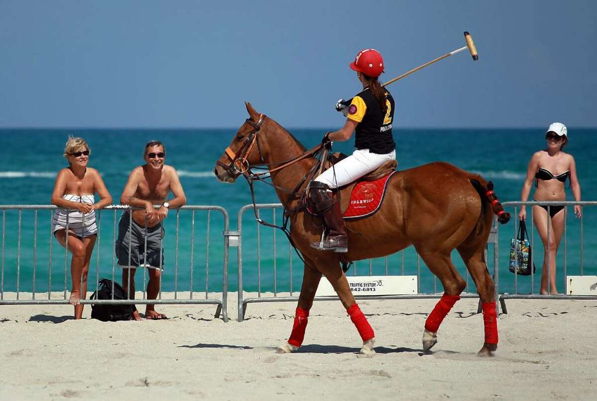 MIAMI BEACH - APRIL 22: Beach goers watch a polo player during the AMG South Beach Women's Polo Cup on April 22, 2010 in Miami Beach, Florida. The women's tournament attracts top players for the beach-side matches. The men's AMG Miami Beach Polo World Cup tournament starts Friday and runs through Sunday. (Photo by Joe Raedle/Getty Images)